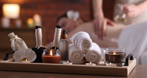 Photo of Woman receiving back massage with oil indoors, focus on different spa supplies
