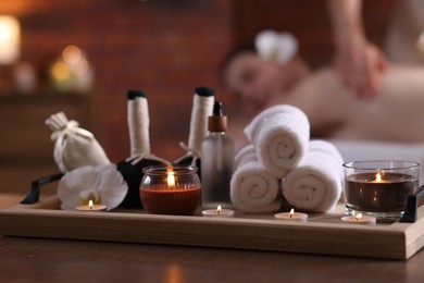 Photo of Woman receiving back massage with oil indoors, focus on different spa supplies
