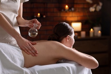 Photo of Woman receiving back massage with oil in spa salon