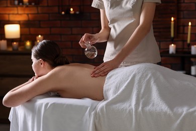 Photo of Woman receiving back massage with oil in spa salon