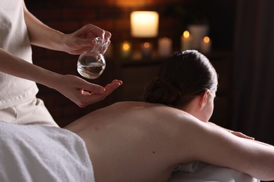 Photo of Woman receiving back massage with oil in spa salon