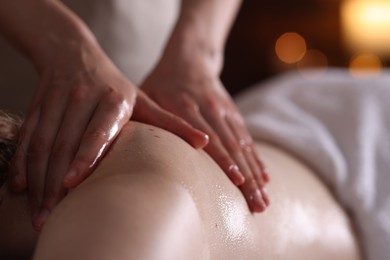 Photo of Woman receiving back massage with oil in spa salon, closeup