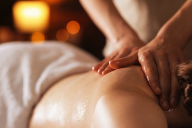 Photo of Woman receiving back massage with oil in spa salon, closeup