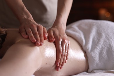 Photo of Woman receiving back massage with oil in spa salon, closeup