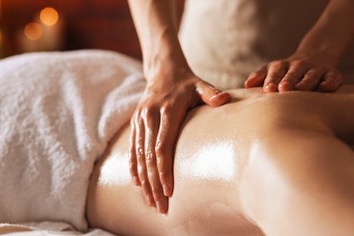 Photo of Woman receiving back massage with oil in spa salon, closeup