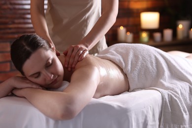 Photo of Woman receiving back massage with oil in spa salon