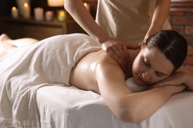 Photo of Woman receiving back massage with oil in spa salon