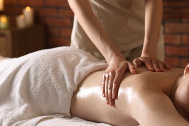 Photo of Woman receiving back massage with oil in spa salon, closeup