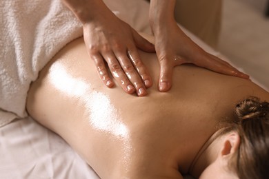Photo of Woman receiving back massage with oil in spa salon, closeup