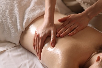 Photo of Woman receiving back massage with oil in spa salon, closeup