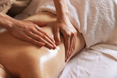 Photo of Woman receiving back massage with oil in spa salon, closeup