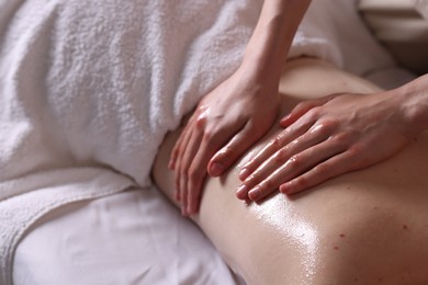 Photo of Woman receiving back massage with oil in spa salon, closeup
