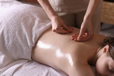 Photo of Woman receiving back massage with oil in spa salon, closeup