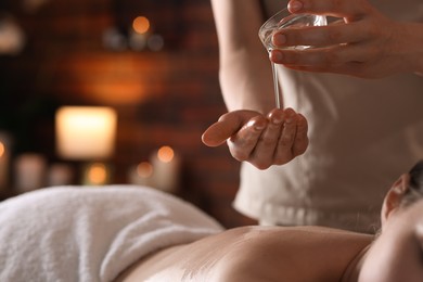 Photo of Woman receiving back massage with oil in spa salon, closeup