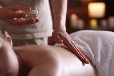 Photo of Woman receiving back massage with oil in spa salon, closeup