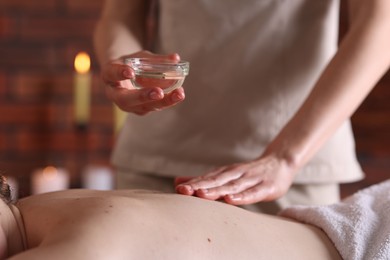 Photo of Woman receiving back massage with oil in spa salon, closeup