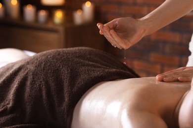 Photo of Woman receiving back massage with oil in spa salon, closeup