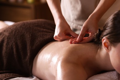 Photo of Woman receiving back massage with oil in spa salon, closeup