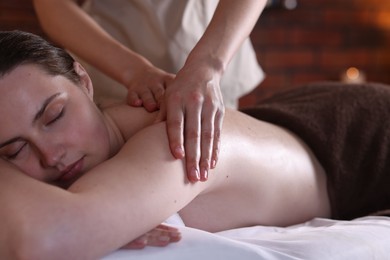 Photo of Woman receiving back massage with oil in spa salon