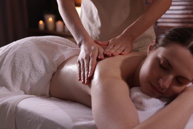 Photo of Woman receiving back massage with oil in spa salon
