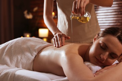 Photo of Woman receiving back massage with oil in spa salon