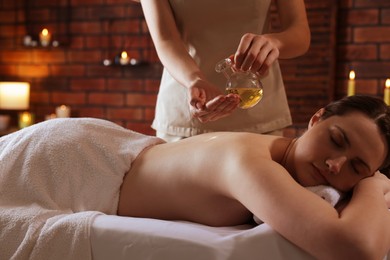 Photo of Woman receiving back massage with oil in spa salon