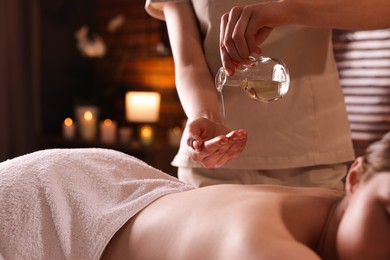 Photo of Woman receiving back massage with oil in spa salon, closeup