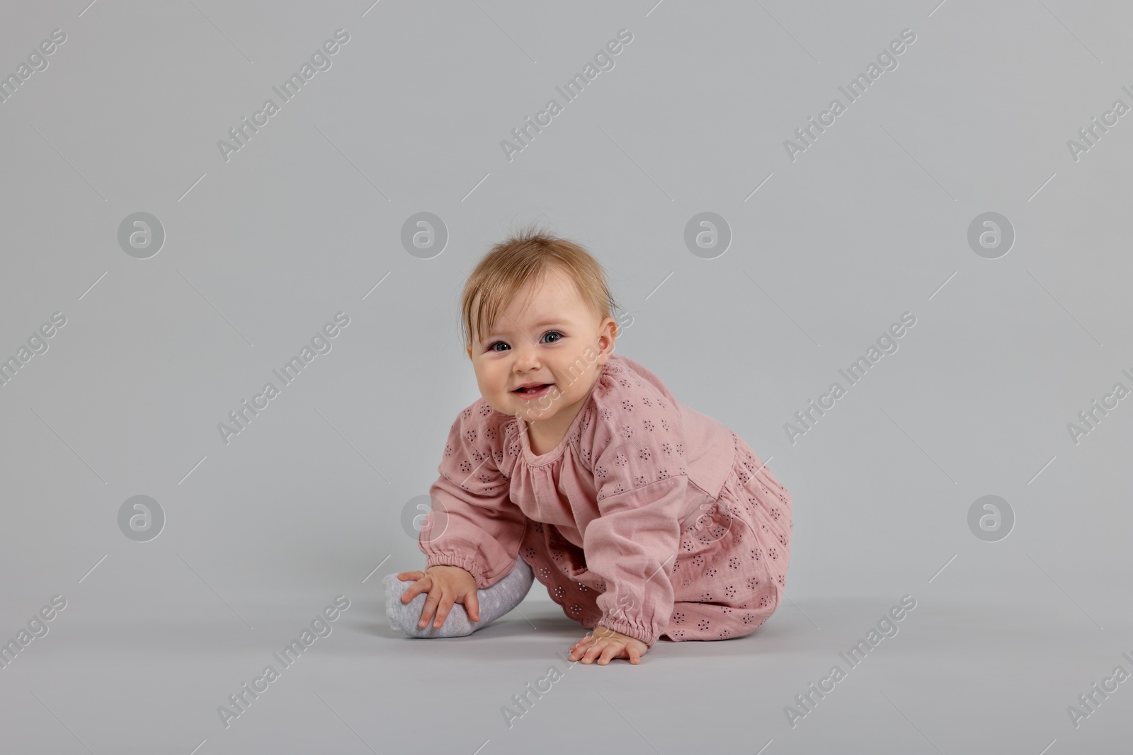 Cute little baby crawling on light grey background Photo of Cute little baby crawling on light grey background