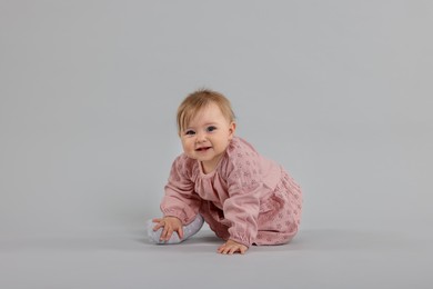 Photo of Cute little baby crawling on light grey background
