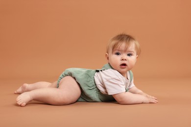 Photo of Portrait of cute little baby on pale brown background