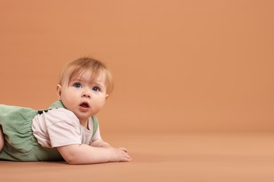 Photo of Cute little baby on pale brown background, space for text