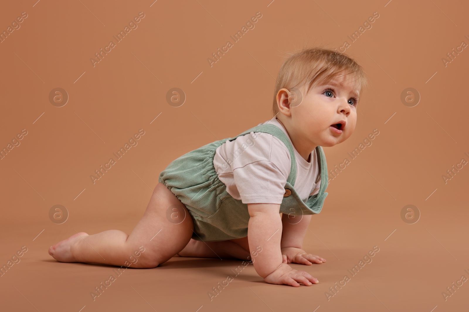 Cute little baby crawling on pale brown background Photo of Cute little baby crawling on pale brown background