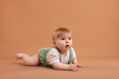 Photo of Cute little baby on pale brown background, space for text