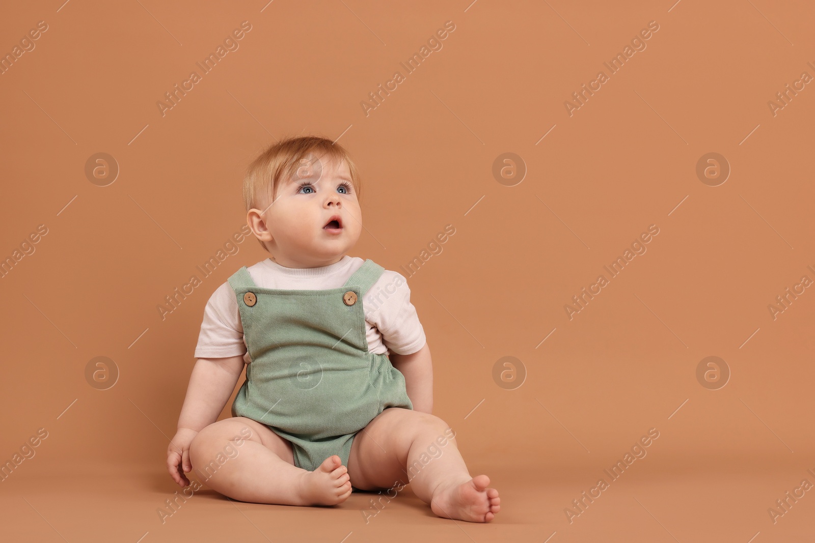 Cute little baby on pale brown background, space for text Photo of Cute little baby on pale brown background, space for text