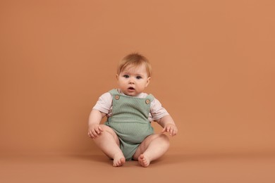 Photo of Cute little baby on pale brown background