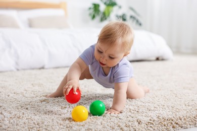 Photo of Cute little baby playing with toys on floor indoors