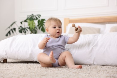 Photo of Cute little baby playing with rattle on floor indoors