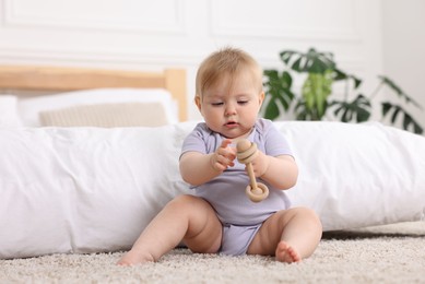 Photo of Cute little baby playing with rattle on floor indoors