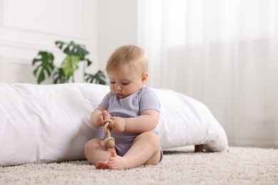 Photo of Cute little baby playing with rattle on floor indoors