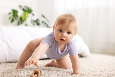 Photo of Cute little baby playing with rattle on floor indoors