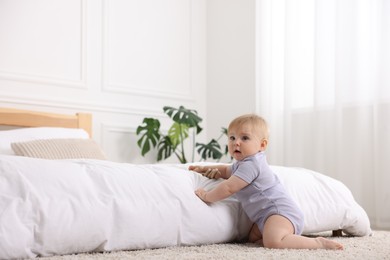 Photo of Cute little baby near bed at home