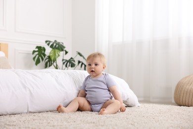 Photo of Cute little baby near bed at home
