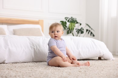 Photo of Cute little baby near bed at home