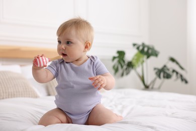 Photo of Cute little baby with rattle on bed at home, space for text