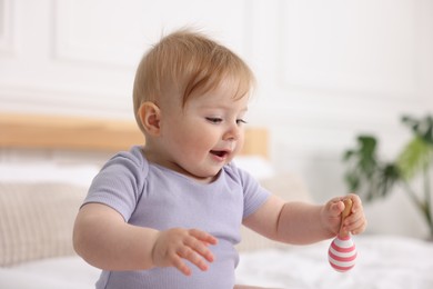Photo of Cute little baby with rattle on bed at home