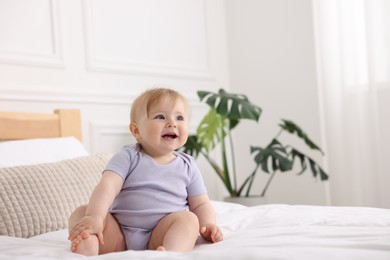 Photo of Cute little baby on bed at home, space for text