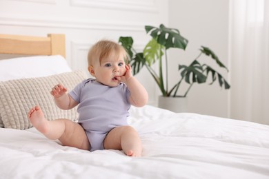 Photo of Cute little baby on bed at home, space for text