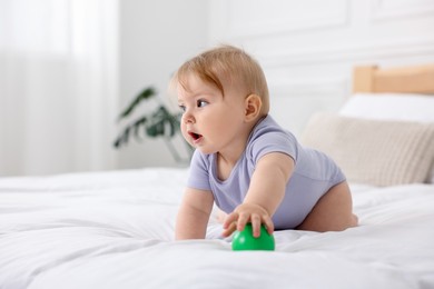 Photo of Cute little baby with toy on bed at home, space for text