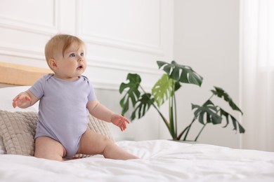 Photo of Cute little baby on bed at home, space for text