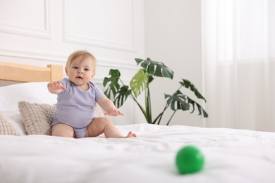 Photo of Cute little baby on bed at home, space for text